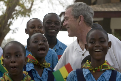 US President George W. Bush listens to schoolchildren sing as he visits a project backed by USAID in Accra, Ghana in 2008