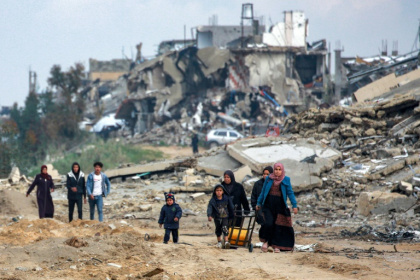 Women and children walk along a destroyed road in Beit Lahia, in the northern Gaza Strip