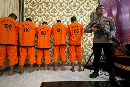 A policeman guards suspected poachers over their involvement in the killing of critically endangered Javan rhinos