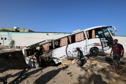An Israeli air strike in the south Gaza city of Khan Yunis leaves a crater that pulls in a bus. - Eyad BABA (AFP) An Israeli air strike in the south Gaza city of Khan Yunis leaves a crater that pulls in a bus. - Eyad BABA (AFP)