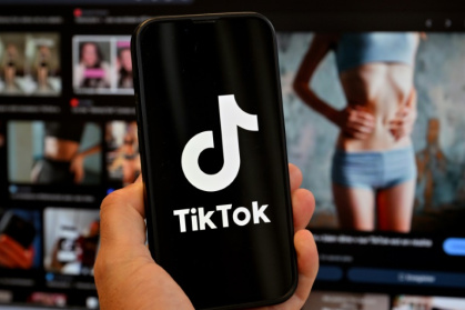 Photo d'illustration du 7 mai 2025 montrant le logo de Tik Tok sur un smartphone devant un écran affichant l'image d'une femme très mince, alors que la tendance .jpg Photo d'illustration du 7 mai 2025 montrant le logo de Tik Tok sur un smartphone devant un écran affichant l'image d'une femme très mince, alors que la tendance .jpg