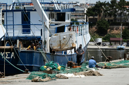 Workers handle a fishing net near a trawler docked at the port of Nea Michaniona, in northern Greece - Sakis Mitrolidis (AFP)