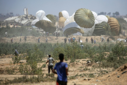 Palestinians rush to the site where parachuted aid packages in the Nuseirat area in the central Gaza Strip - Eyad BABA (AFP) Palestinians rush to the site where parachuted aid packages in the Nuseirat area in the central Gaza Strip - Eyad BABA (AFP)