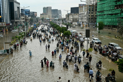 People wade through a flooded street after heavy rainfall in Karachi - Asif HASSAN (AFP)