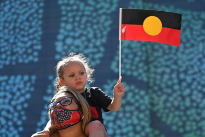 A young girl holds up an Australian Aboriginal flag during a 2022 demonstration in support of Indigenous rights. - Steven Saphore (AFP)