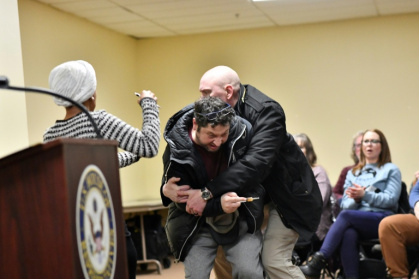 Security restrains a man who sprayed an unknown substance at US Representative Ilhan Omar (left) during a town hall she was hosting in Minneapolis - Octavio JONES (AFP)