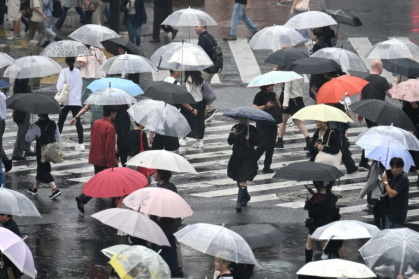 Pedestrians with umbrellas walk on a crossing as rain falls in Tokyo's Shibuya district - Rie KIKUCHI (AFP)