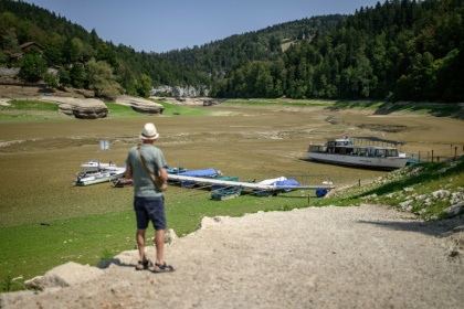A tourist looking at the parched bed of the Lac des Brenets, which is on the border between Switzerland and France - Fabrice COFFRINI (AFP)